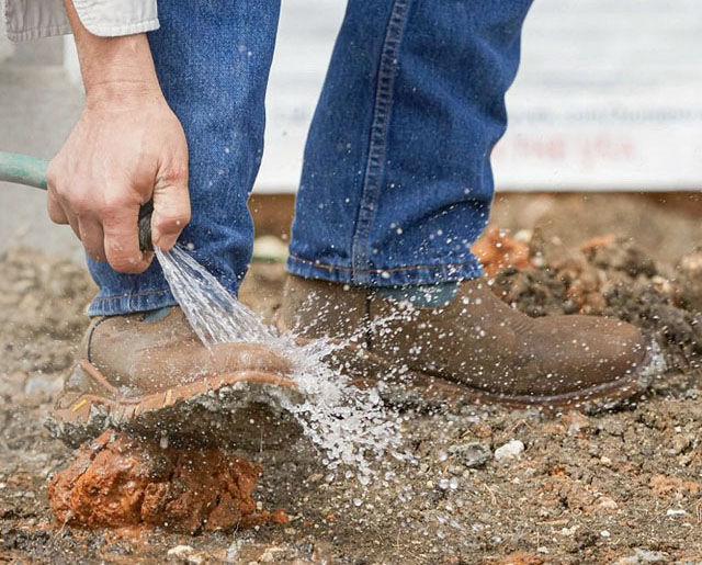 Man hosing off TLX Boom 11" Pull-On Waterproof Work Bootwork boots.